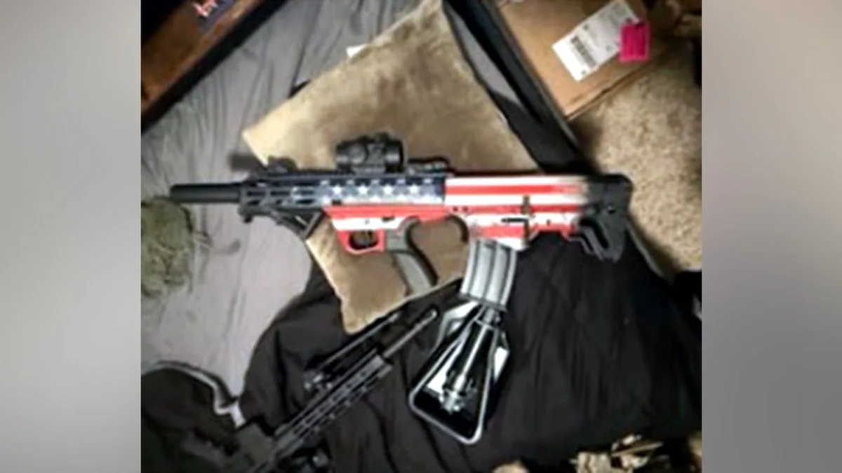 Un rifle tipo AR-15 con acabado decorado con la bandera de Estados Unidos sobre una cama.