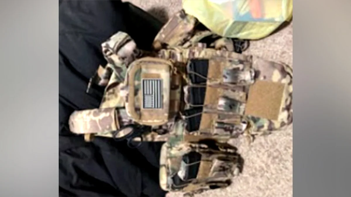 Un chaleco táctico de camuflaje con parches y bolsillos extendidos sobre una superficie.