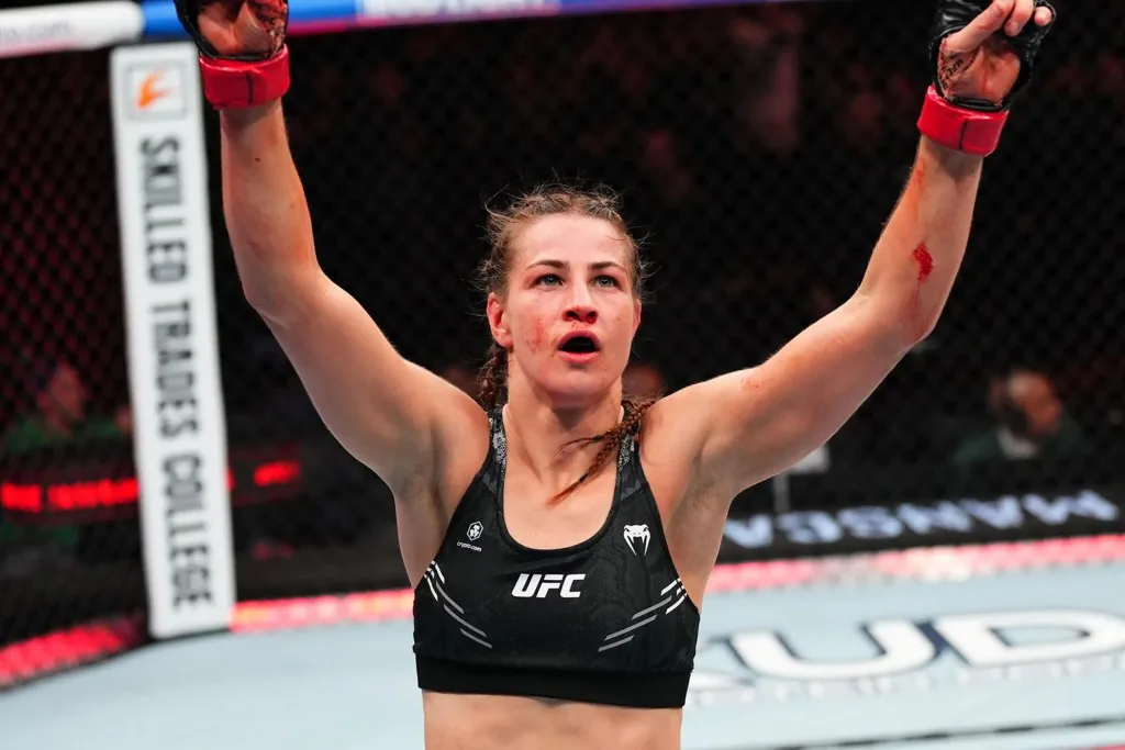 La peleadora de UFC celebra con ambos brazos en alto dentro del octágono.
