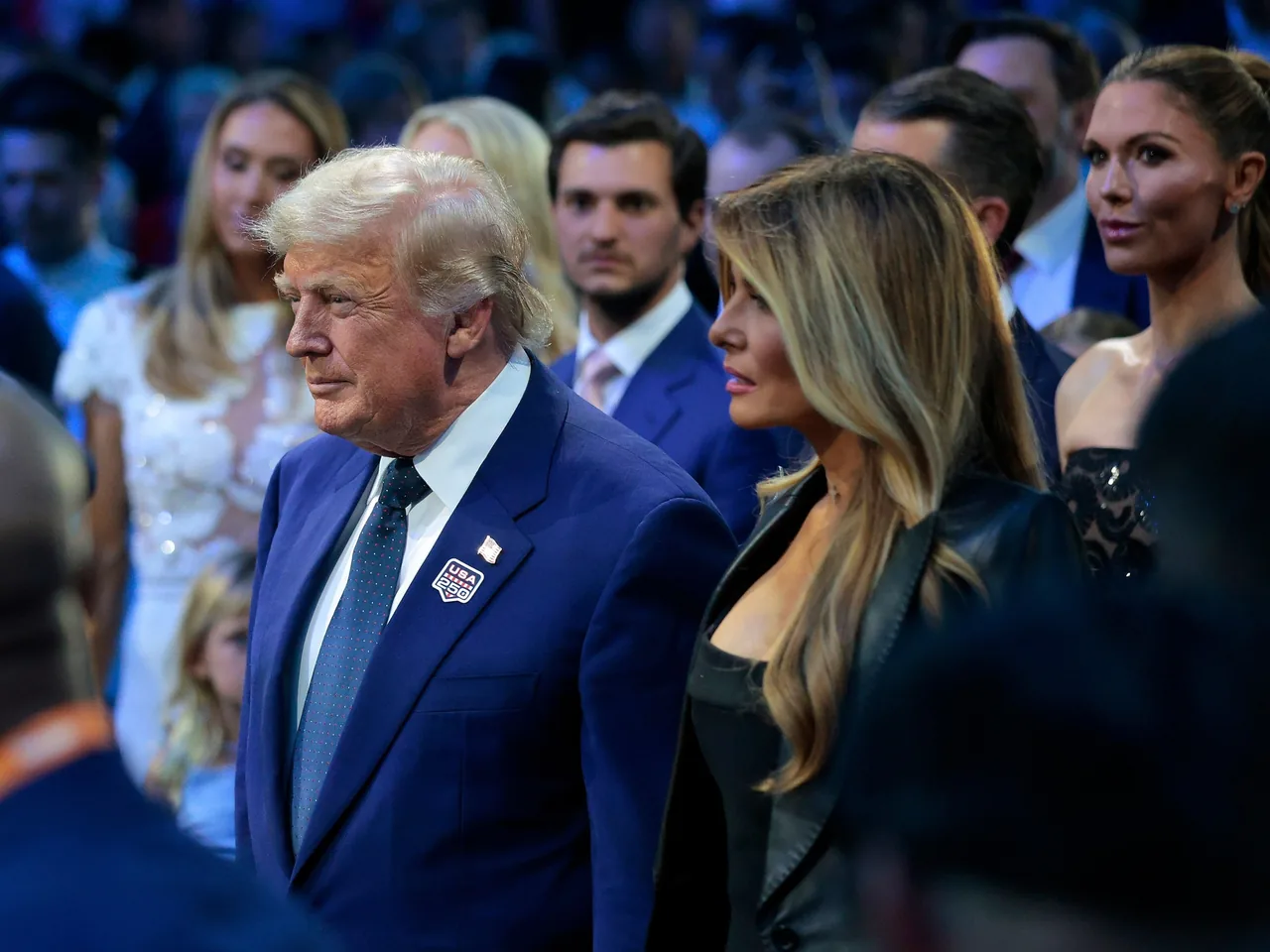Donald Trump asiste a un acto público junto a Melania Trump, con un distintivo de “USA 250” en la solapa.