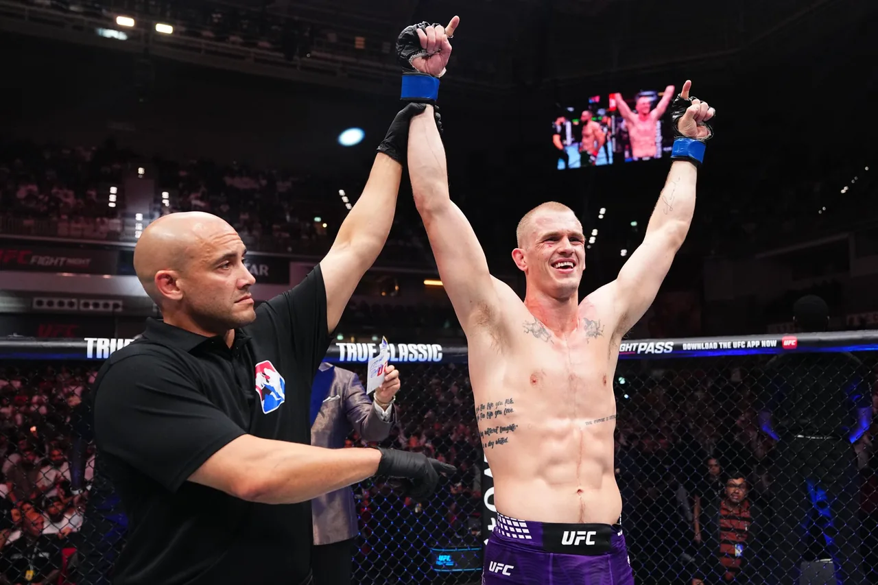 Un árbitro levanta el brazo del luchador tras su victoria en un combate de UFC.