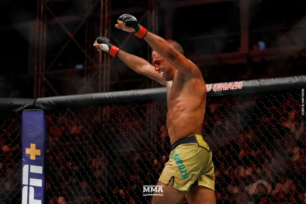 Un peleador de MMA, ensangrentado, celebra con los brazos en alto dentro de la jaula.