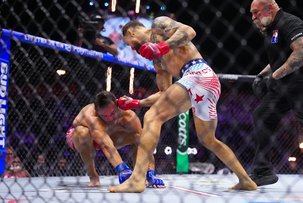 Un peleador conecta un golpe durante un combate de artes marciales mixtas en la jaula, mientras el árbitro observa de cerca.