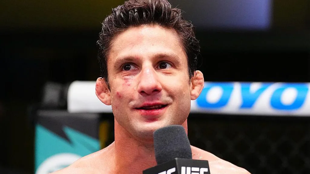 Un luchador de UFC, con el rostro magullado, habla ante un micrófono después del combate.