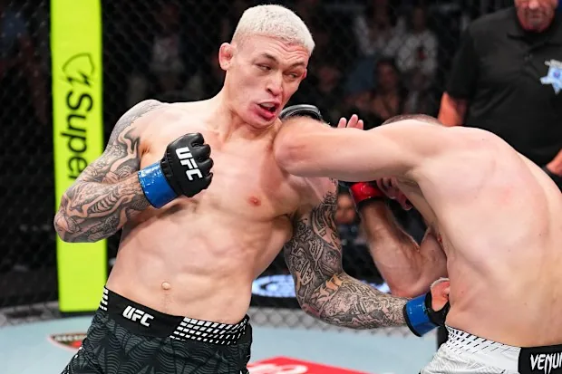 Un luchador de UFC conecta un golpe al rostro de su rival durante un combate en la jaula.