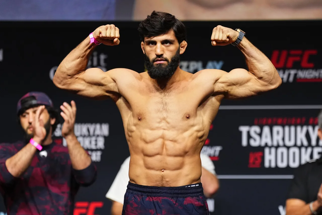Un peleador de UFC posa flexionando los bíceps en el pesaje oficial.