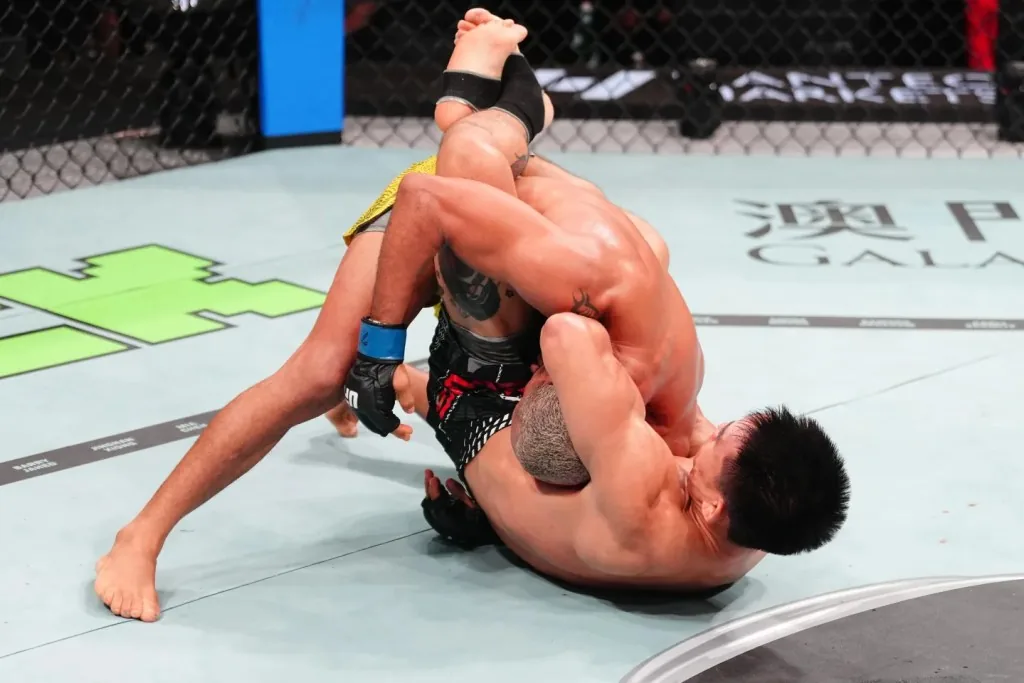 Dos luchadores de artes marciales mixtas pelean en el suelo dentro del octágono de la UFC.