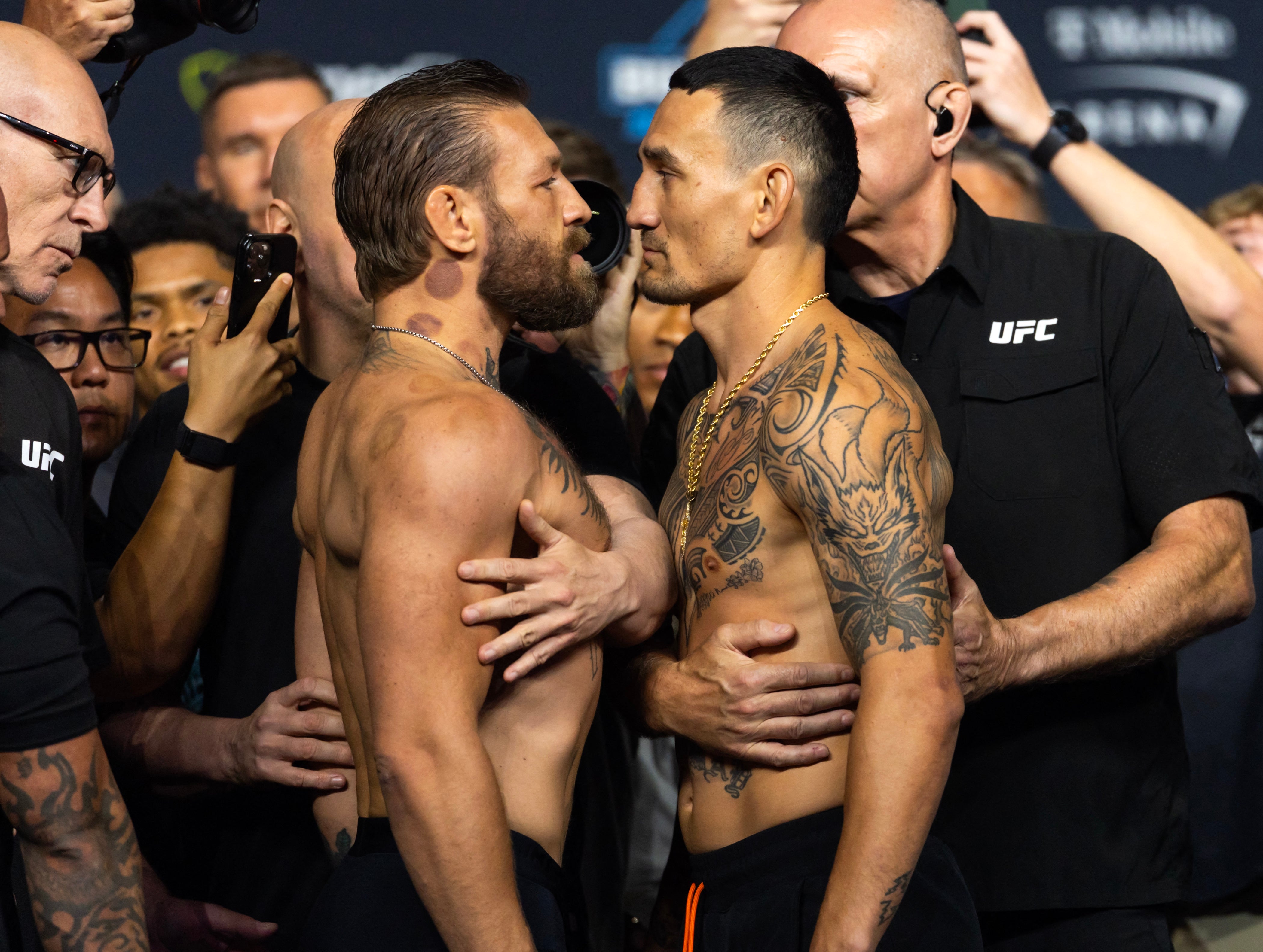 Conor McGregor (left) faces off with Max Holloway during weigh ins